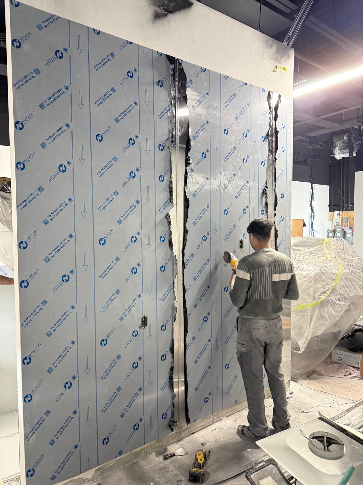 Stainless steel sheets being installed on a commercial wall